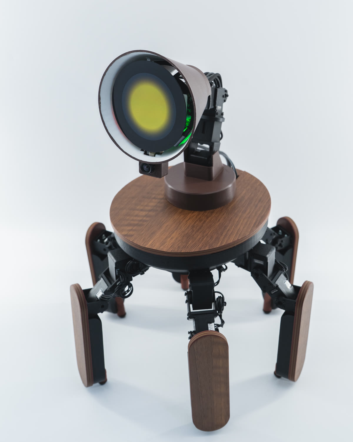 Palmimo DevKit seen from slightly above the front: a round wood-grain top, six legs, and a round display for a face.